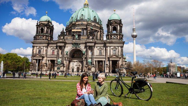 Two students sitting on grass in front of church in Berlin
