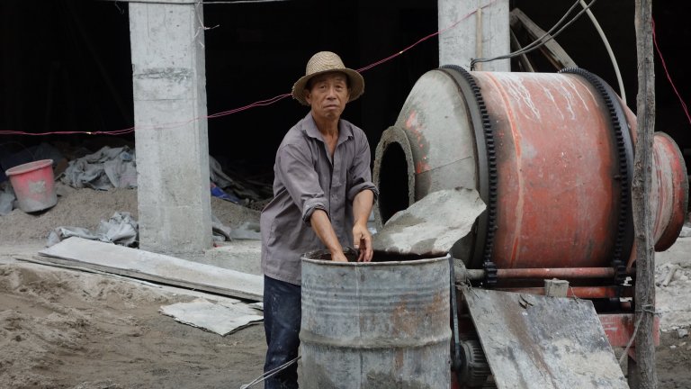 Man mixies cement in a construction site in China.