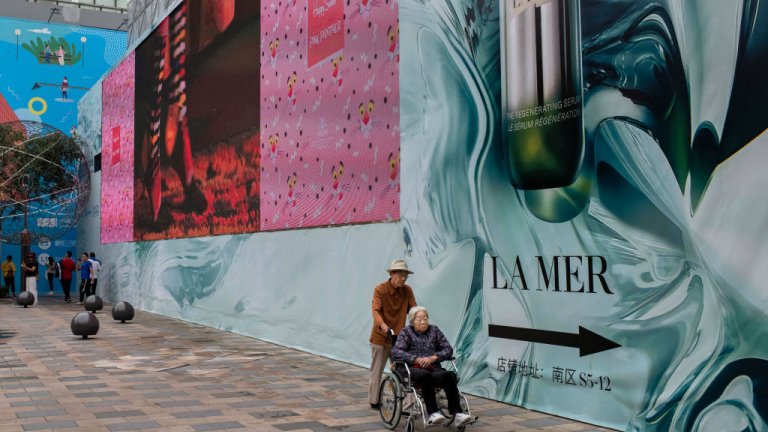 n elderly Chinese man pushes an elderly woman in a wheelchair through a local shopping mall in Beijing, China