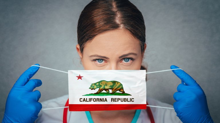 Women doctor holds a surgical mask with the California Republic flag.