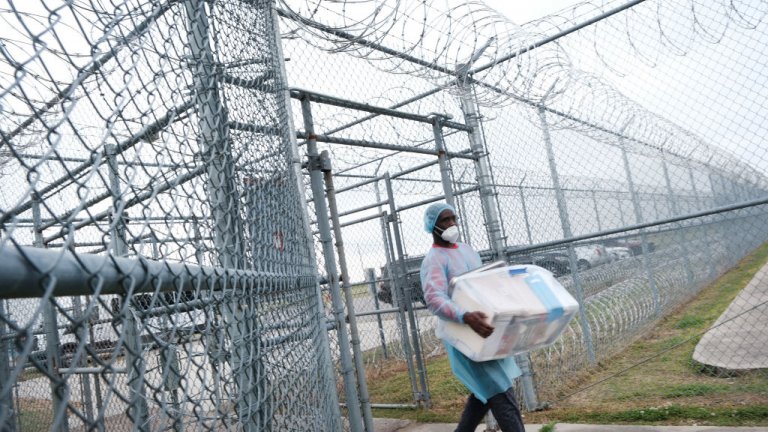 A health-care worker carries COVID-19 vaccines into a prison.
