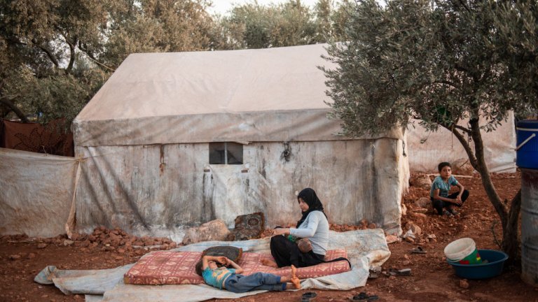 Syrian Refugees sitting in front of tent