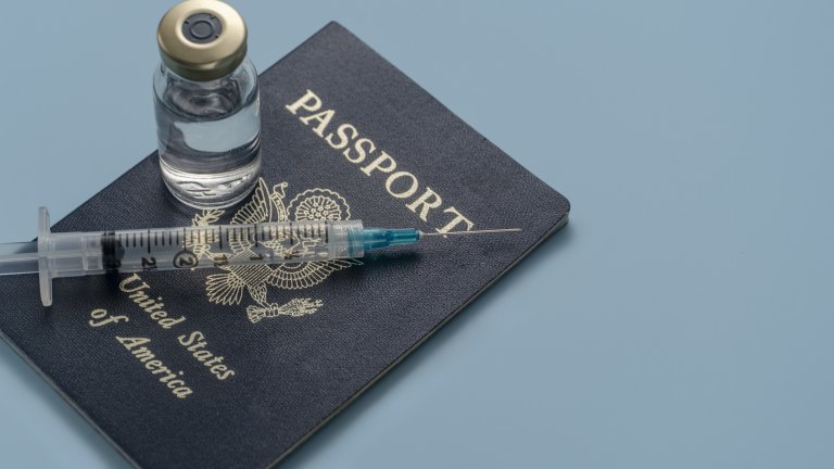 Photo fo a U.S. passport with a vaccine bottle and syringe