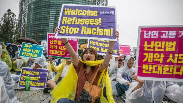Demonstrators in South Korea sitting on the ground and carrying signs in Korean