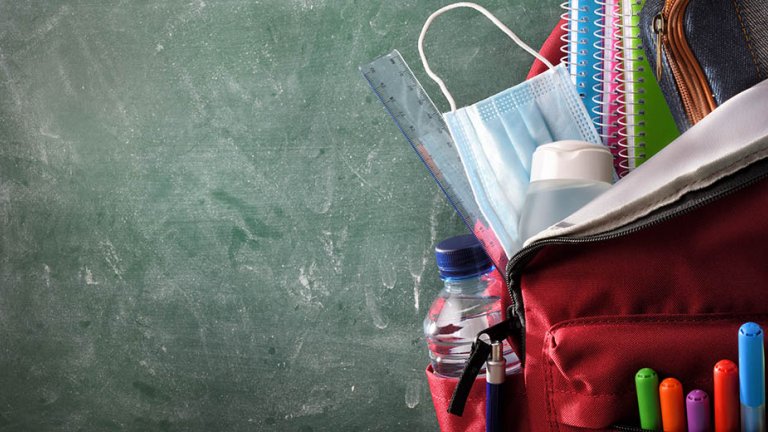 A surgical mask is tucked into a pupil's school backpack.
