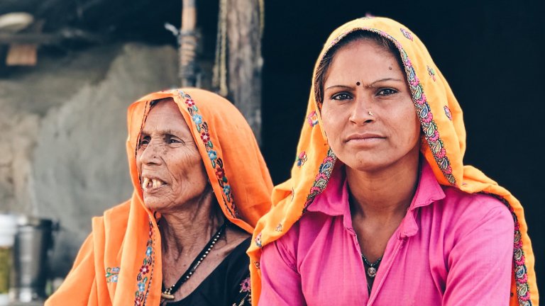 Two women sitting outdoor in Khidarpur Jadoo, Rajasthan, India.