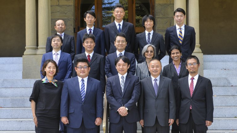 2017-18 cohort of APARC's Global Affiliates Program posing to the camera at the entrance to Encina Hall, Stanford.