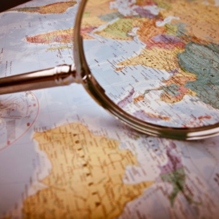 a magnifying glass focused on Asia on a map
