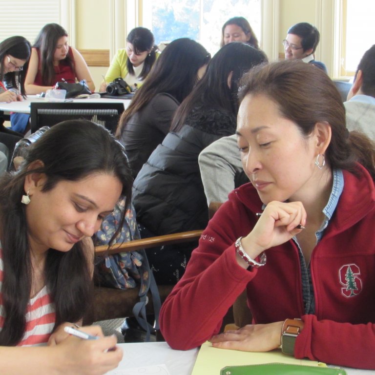 Two female Global Affiliate visiting fellows seated at a desk, during a collaborative study session.