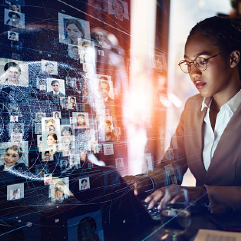 woman on computer in front of computer screen of faces