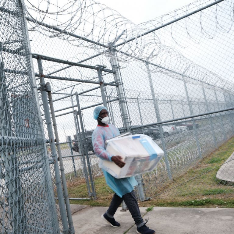 A health-care worker carries COVID-19 vaccines into a prison.