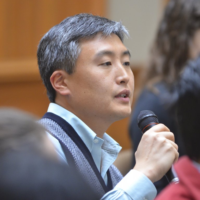 APARC faculty Yong Suk Lee speaks to a microphone among audience members during a Q&A session.