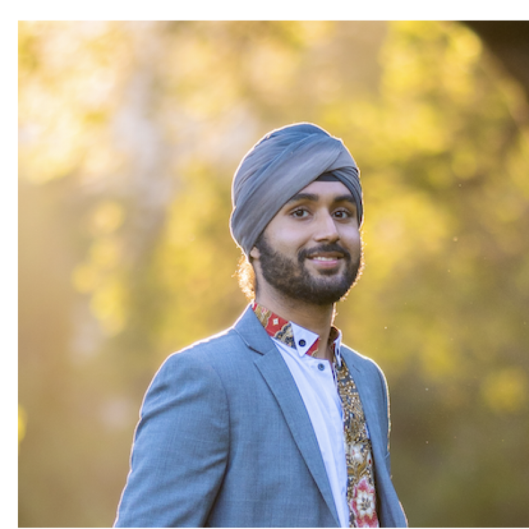 A headshot of Jasdeep Hundal. Jasdeep is standing outside with soft light.