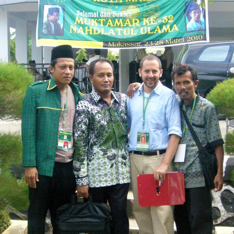 Shorenstein postdoctoral fellow alum Jeremy Menchik posing for the camera with three local men during a visit in Southeast Asia.