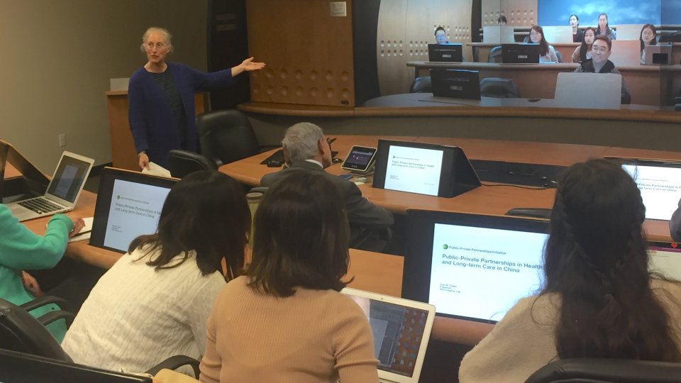 Karen Eggleston speaking in front of students and scholars at an AHPP workshop in a Stanford videoconferencing classroom