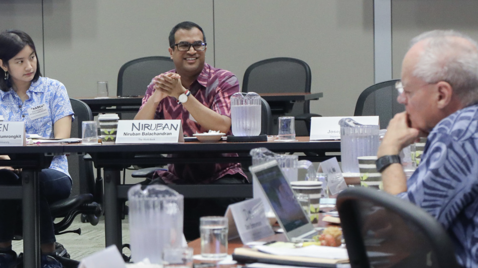 Two men and a woman seated in a conference room conversing
