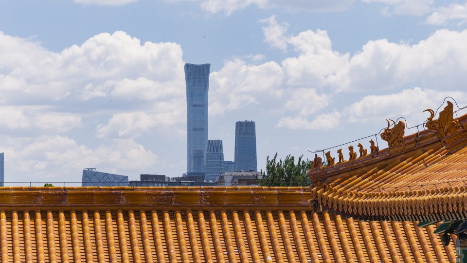 View of building roof in the Forbidden City complex and the Beijing skyline in the background