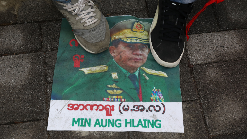 Protesters in Myanmar stand on a picture of General Min Aung Hlaing