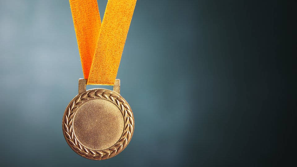 Close-Up Of Gold Medal Against Blackboard