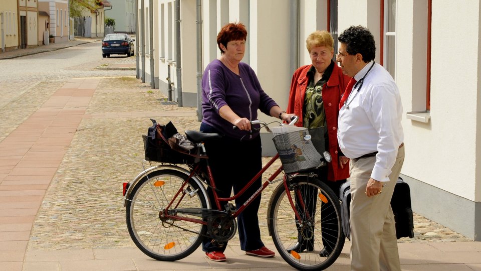 Medical doctor chats with local residents while making housecalls