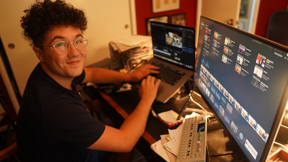 A young men sitting at a desk in front of computer monitors