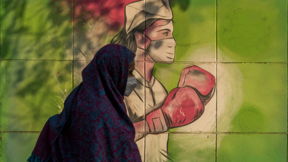 A woman walks past a mural referring to the Covid-19 coronavirus painted on a wall on December 10, 2020 in New Delhi, India.