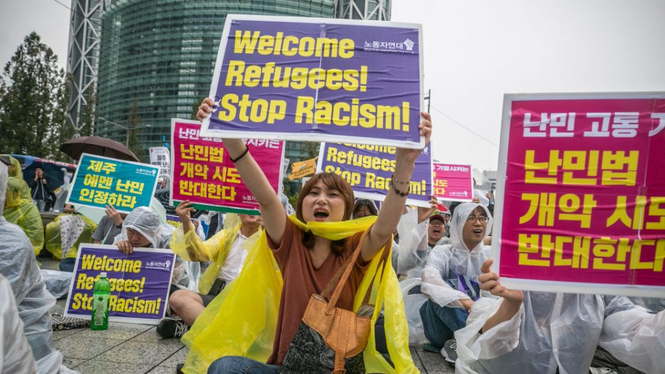 Demonstrators in South Korea sitting on the ground and carrying signs in Korean