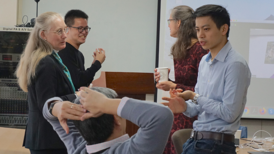 Two women and three men talking with each other in a conference room