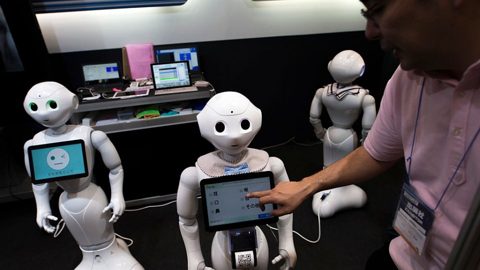 An attendant uses a tablet computer on a SoftBank Group Corp.'s Pepper humanoid robot at the Robodex Trade Show, Tokyo, Japan, 2017