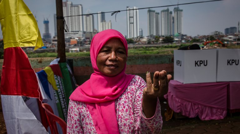 A woman shows her fingers marked with ink after voting at a polling station on April 17, 2019 in Jakarta, Indonesia.