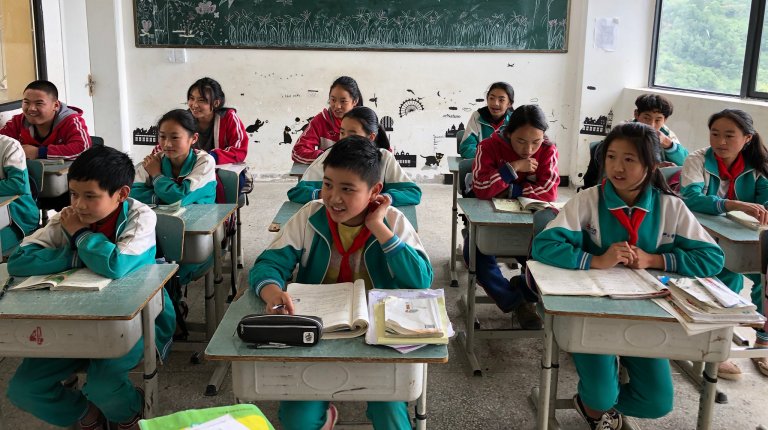 Uniformed kids sitting at desks in a classroom.