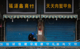 A security guard sits outside a closed market in Wuhan, China.