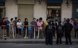 A mix of ethnic Uyghur and Han shopkeepers hold large wooden sticks as they are trained in security measures on June 27, 2017 next to the old town of Kashgar, in the far western Xinjiang province
