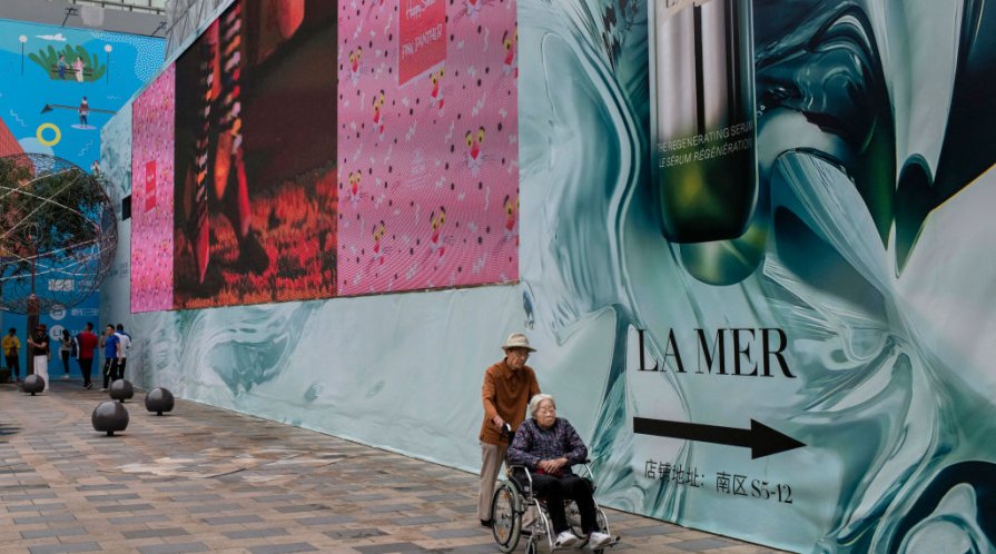 n elderly Chinese man pushes an elderly woman in a wheelchair through a local shopping mall in Beijing, China