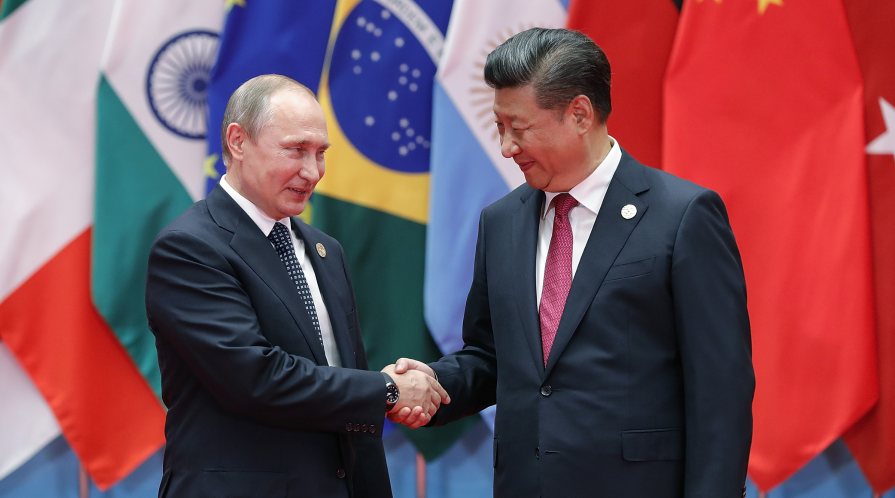 Vladamir Putin and Xi Jinping shake hands.