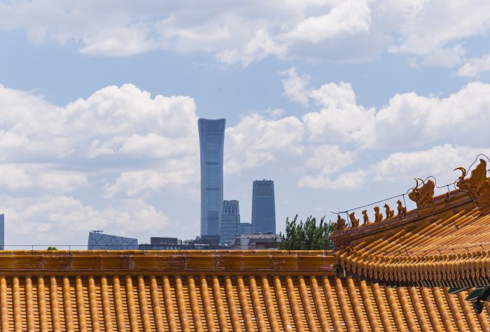 View of building roof in the Forbidden City complex and the Beijing skyline in the background