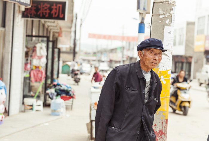 Old man on urban street in China.