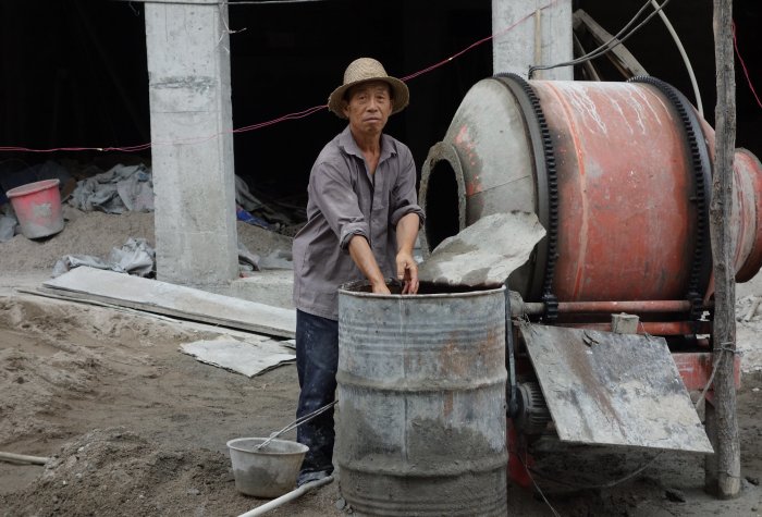 Man mixies cement in a construction site in China.