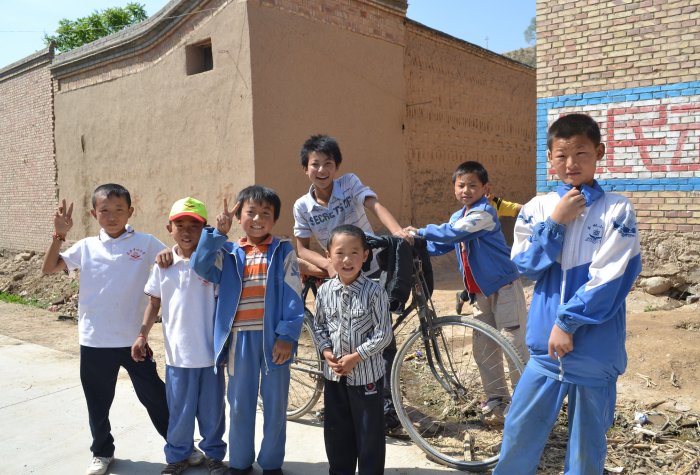 A group of school boys in school uniforms pose in a rural village in China.