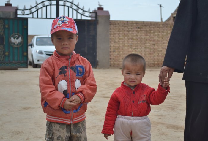 Two young boys stand in a driveway in rural China.