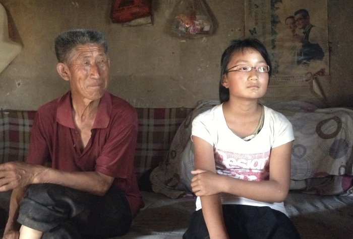 Grandfather and granddaughter sit in home in rural China.