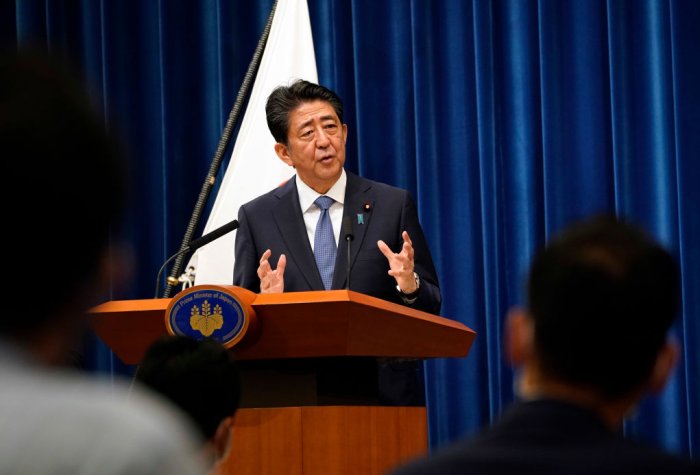 Japanese Prime Minister Shinzo Abe speaks at a podium with audience seen at the front