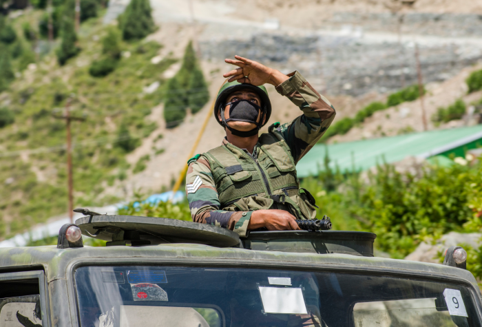 An Indian army soldier watches a fighter plane from a convoy of trucks in Gagangir, India.