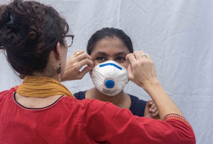 Ashley Styczynski shows a colleague in Bangladesh how to wear an N95 mask to protect her against COVID-19.