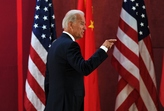 President Biden walks past a row of Chinese and American flags.