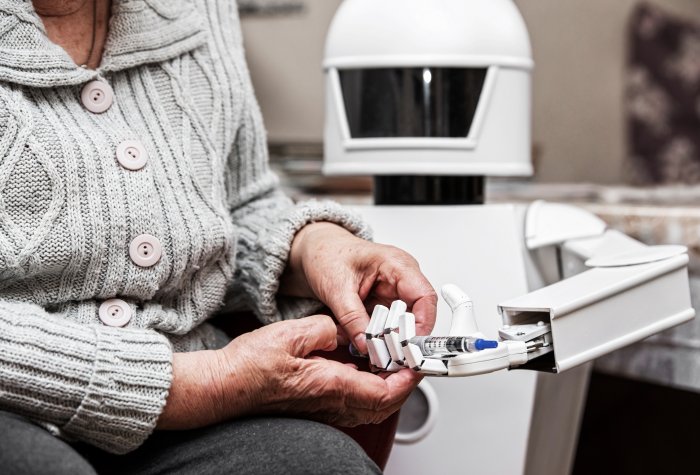 Autonomous caregiver robot is holding a insulin syringe, giving it to an senior adult woman, concept ambient assisted living