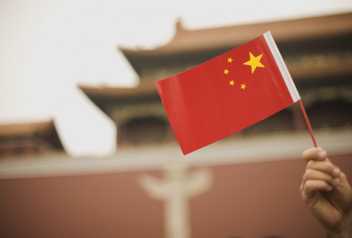 Handheld Chinese flag in front of a government building in Beijing, China.