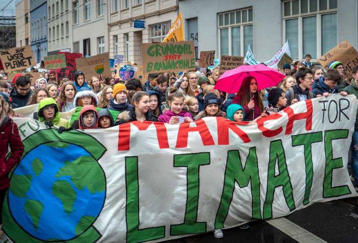 Climate change activists march down a street carrying banners and signs.