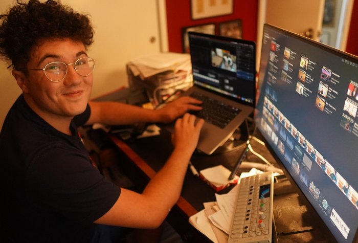 A young men sitting at a desk in front of computer monitors