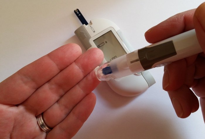 Closeup on hands holding a glucometer